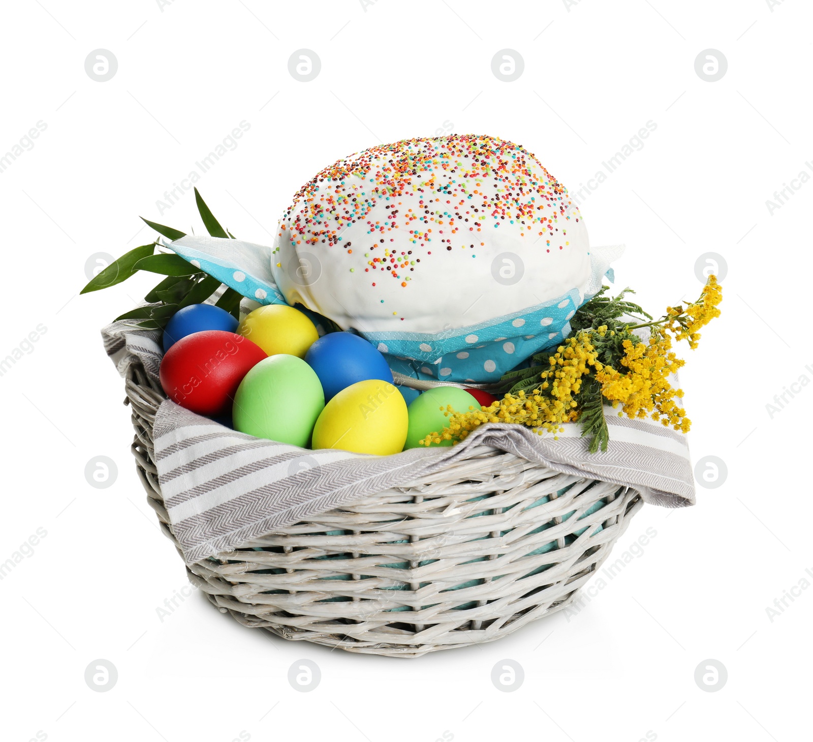 Photo of Basket with delicious Easter cake, dyed eggs and flowers on white background