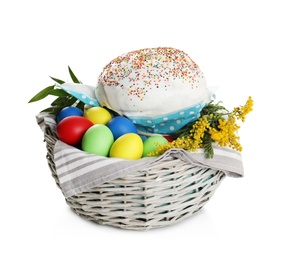 Photo of Basket with delicious Easter cake, dyed eggs and flowers on white background