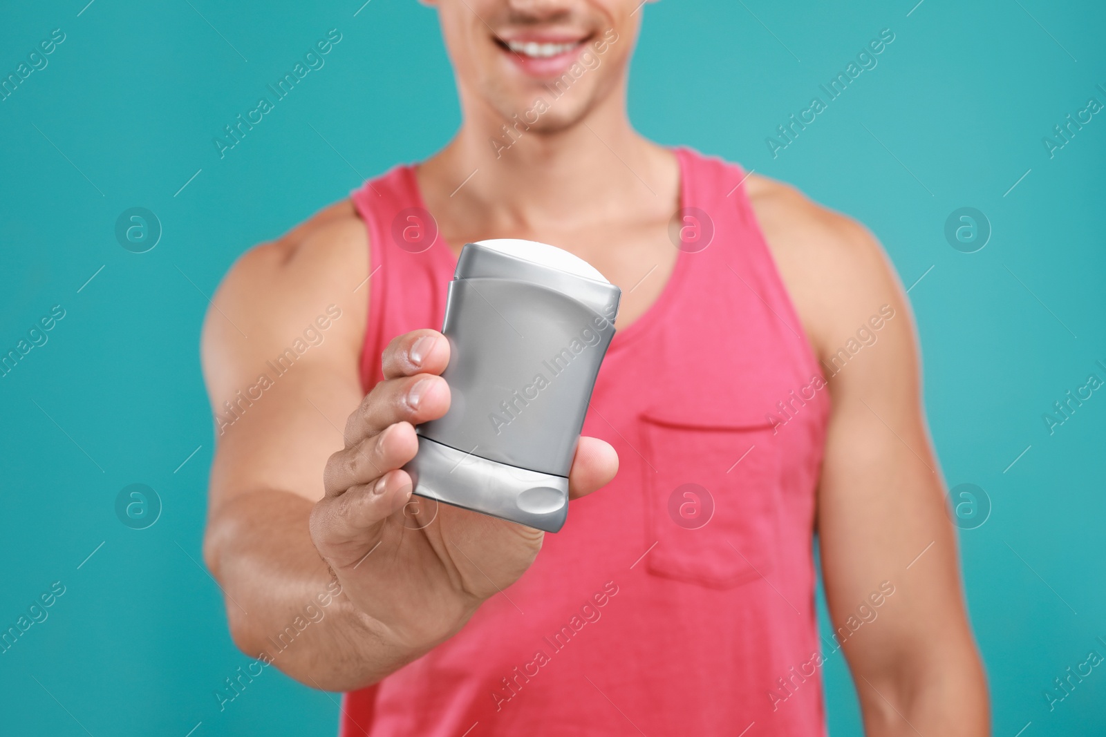 Photo of Young man with deodorant on light blue background, closeup