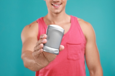 Photo of Young man with deodorant on light blue background, closeup