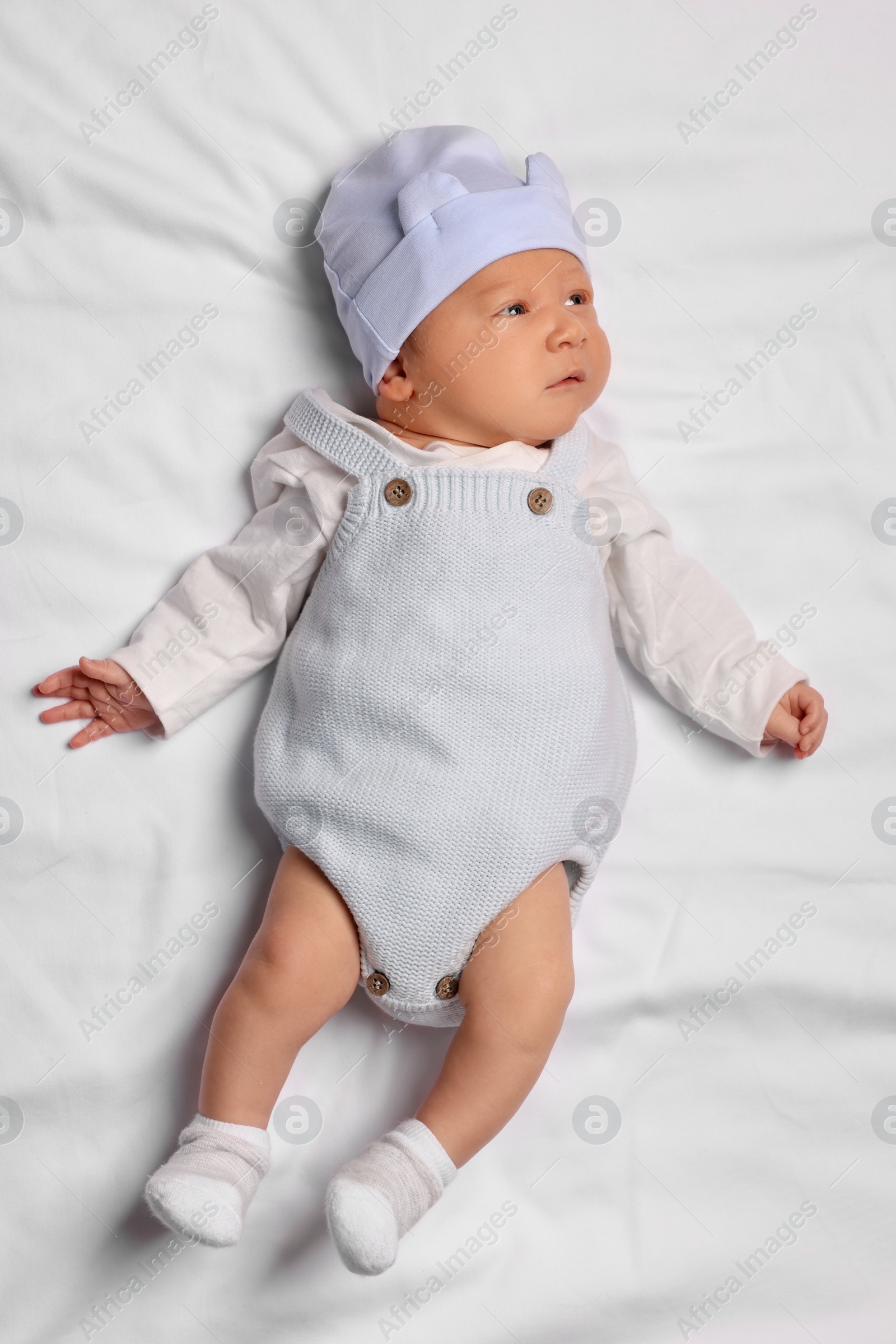 Photo of Cute newborn baby lying on white blanket, top view