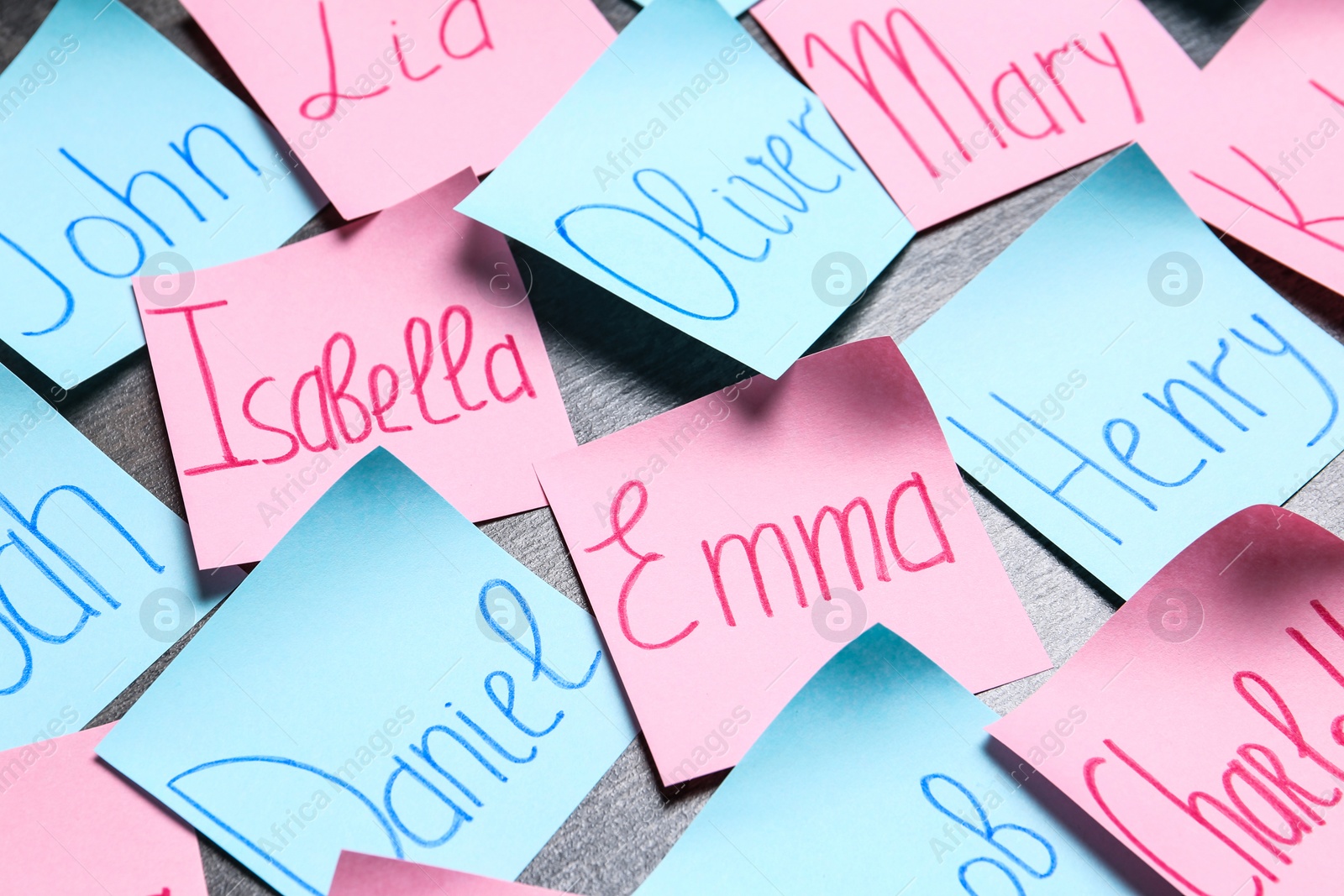 Photo of Paper notes with different baby names on grey background