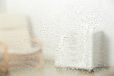 Blurred view of room through glass with water drops, closeup