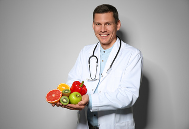 Nutritionist with fresh products on light grey background