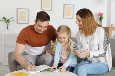 Happy family counting money on sofa at home