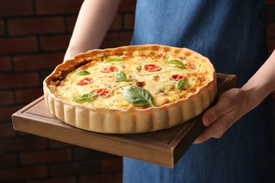 Photo of Woman with delicious homemade cheese quiche indoors, closeup