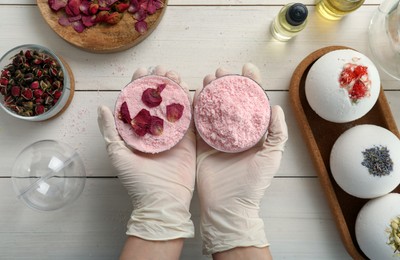 Photo of Woman in gloves making bath bomb at white table , top view