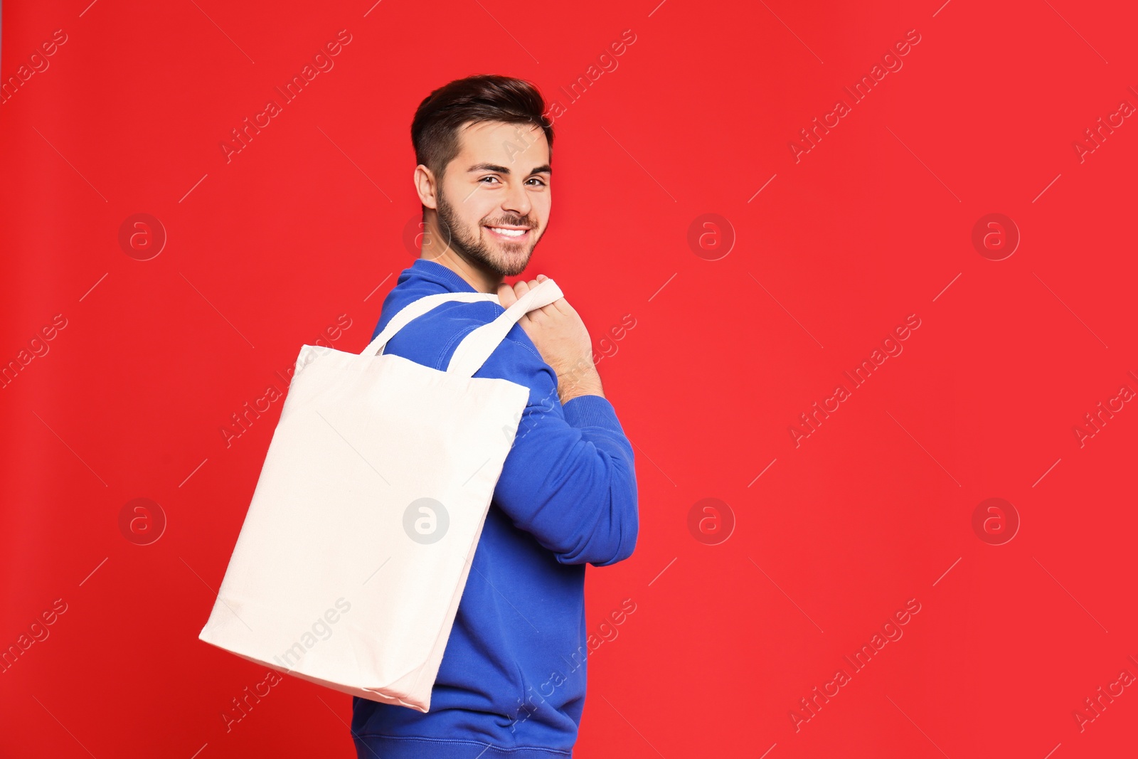 Photo of Portrait of young man with eco bag on red background. Space for text