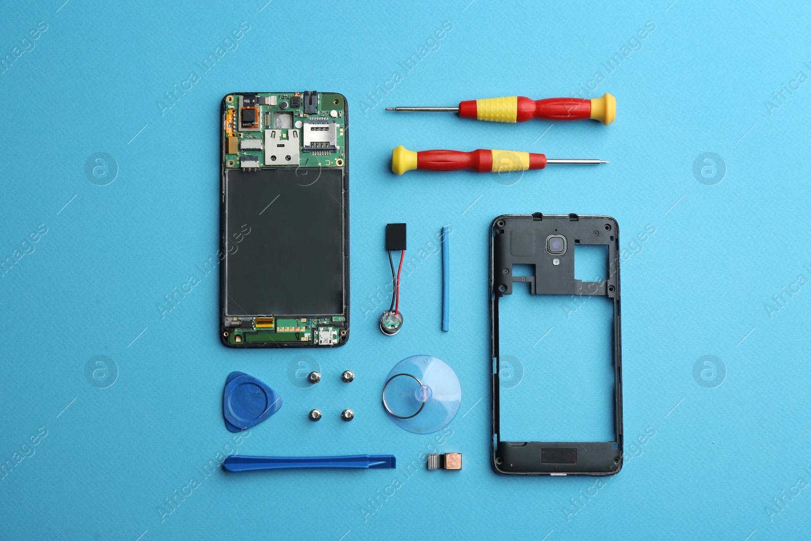 Photo of Disassembled mobile phone and repair tools on blue background, flat lay