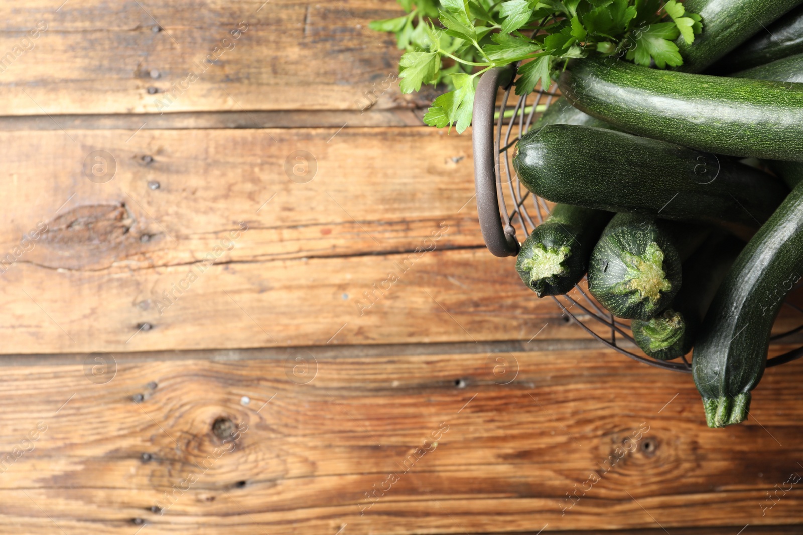 Photo of Basket with green zucchinis on wooden table, flat lay. Space for text