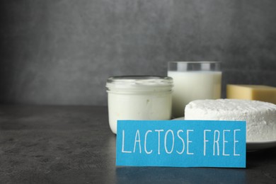 Photo of Card with phrase Lactose free and different fresh products on grey table, space for text