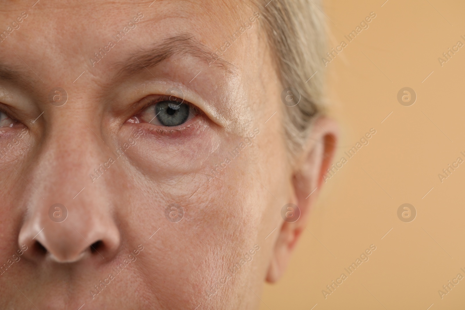 Photo of Woman with beautiful eyes on beige background, macro view. Space for text