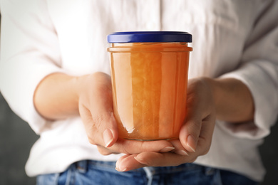 Woman with jar of delicious jam, closeup