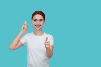 Woman using ear spray on light blue background. Space for text
