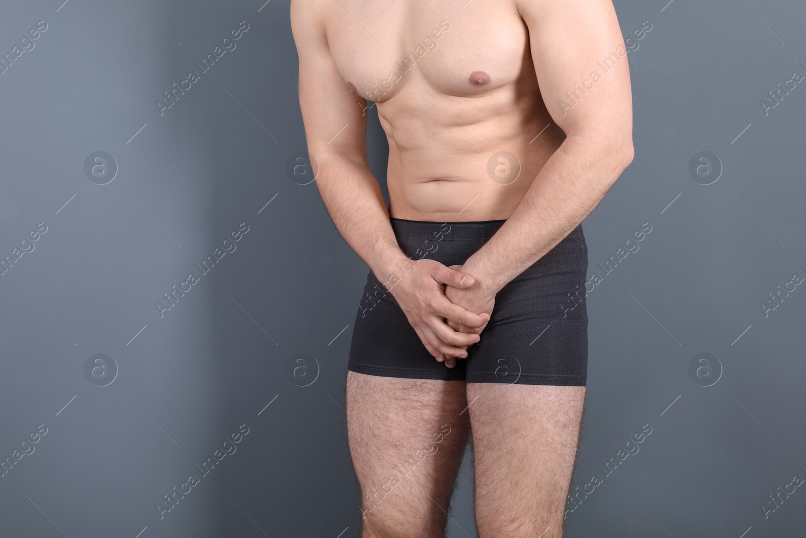 Photo of Young man with urological problems suffering from pain on grey background