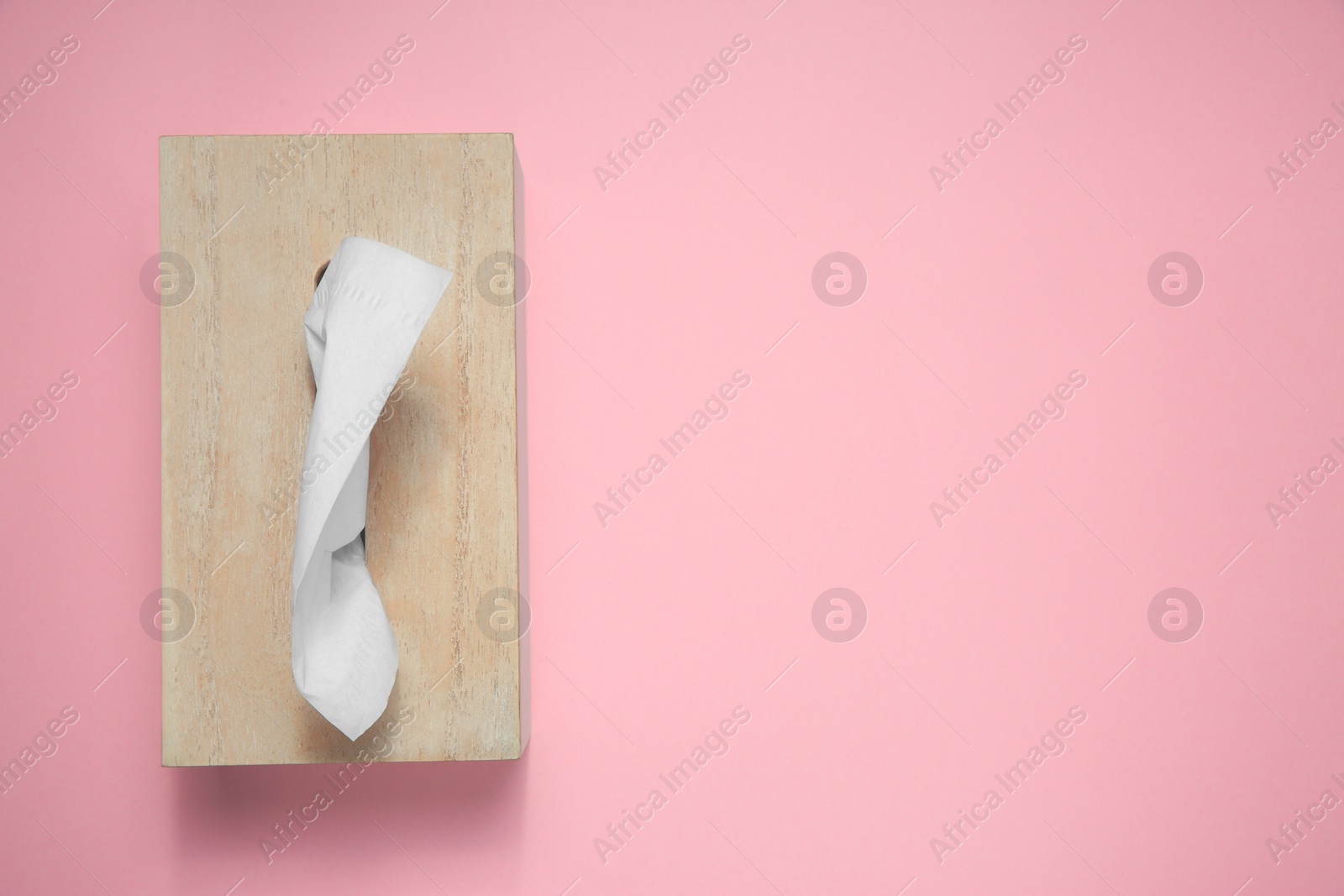 Photo of Wooden holder with paper tissues on pink background, top view. Space for text