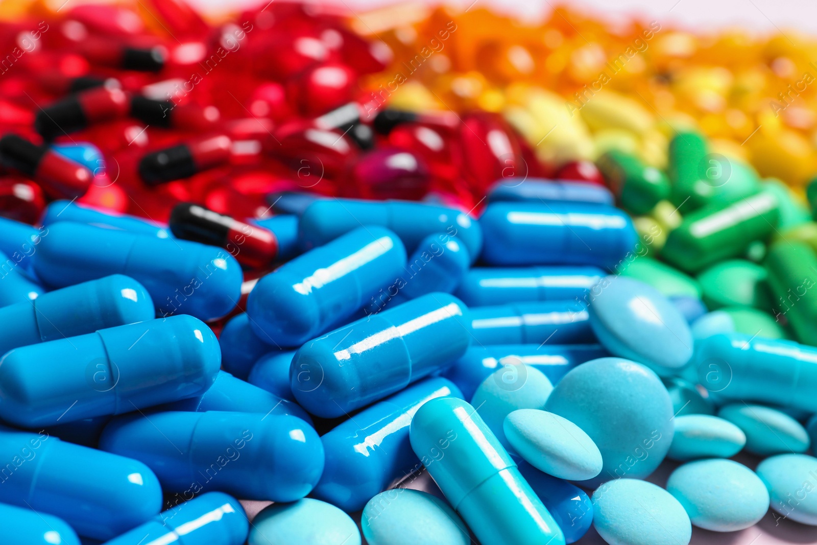 Photo of Heap of different colorful pills on table, closeup