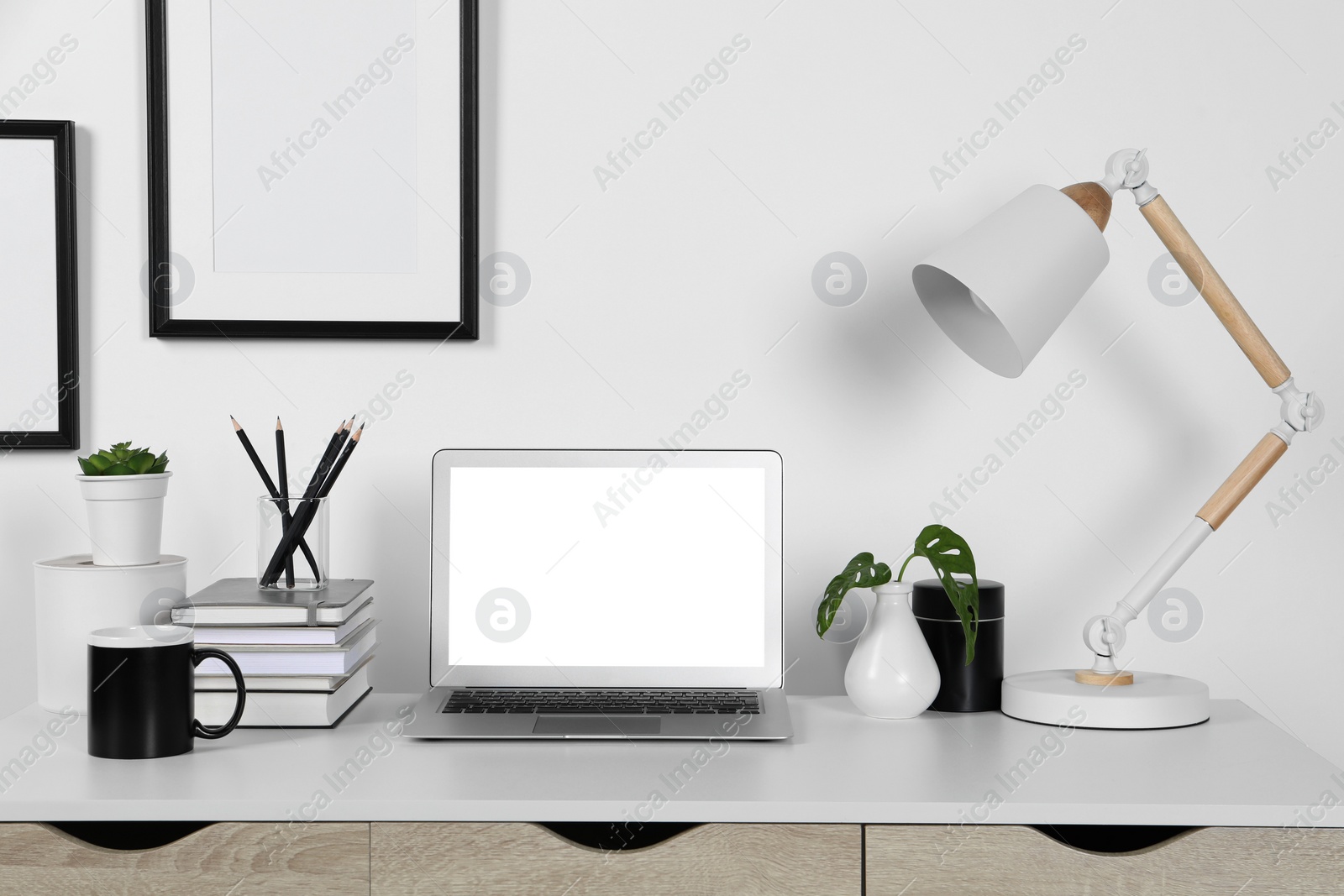 Photo of Home workplace. Laptop, lamp and stationery on white wooden desk