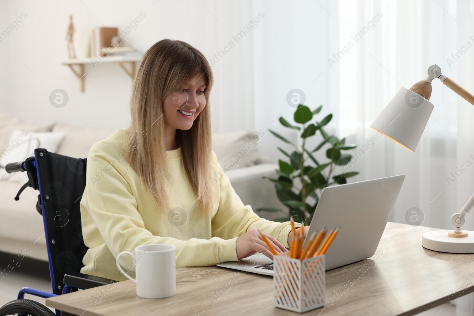 Photo of Woman in wheelchair using laptop at table in home office