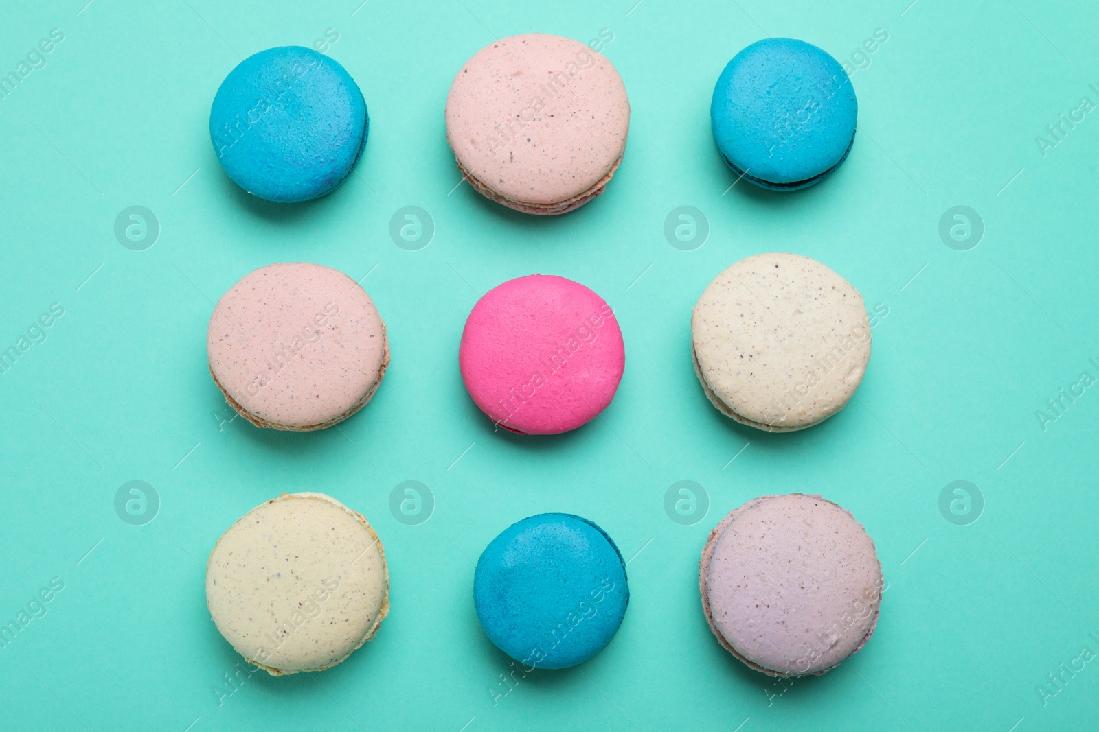 Photo of Delicious colorful macarons on turquoise background, flat lay