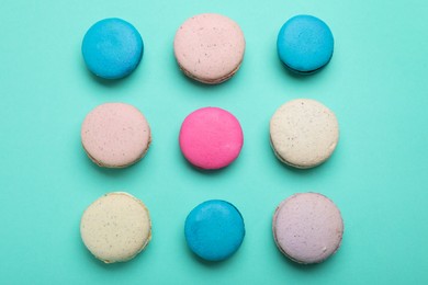 Delicious colorful macarons on turquoise background, flat lay