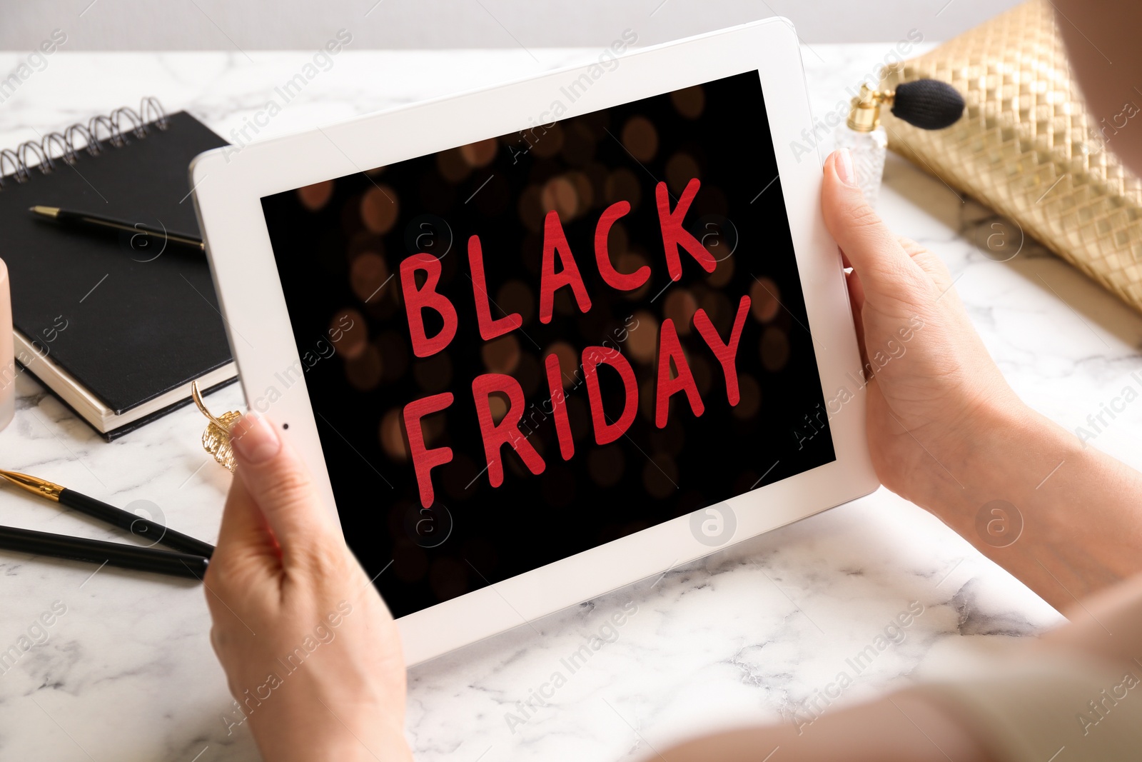 Photo of Woman shopping online using tablet at white marble  table, closeup. Black Friday Sale