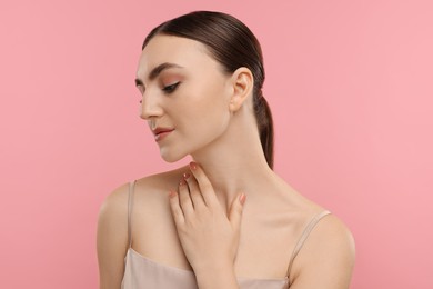 Photo of Beautiful woman touching her neck on pink background