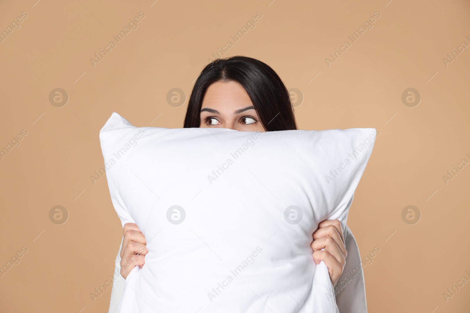 Photo of Young woman with soft pillow on beige background