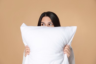 Young woman with soft pillow on beige background