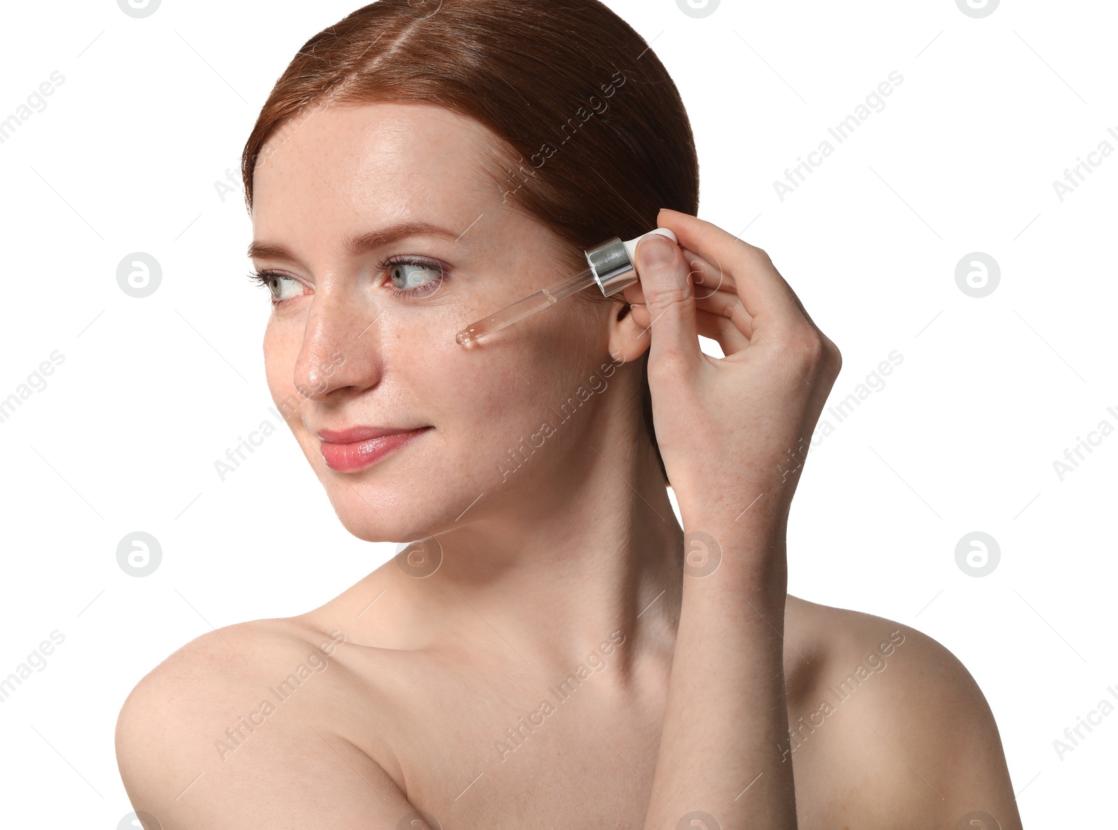 Photo of Beautiful woman with freckles applying cosmetic serum onto her face on white background