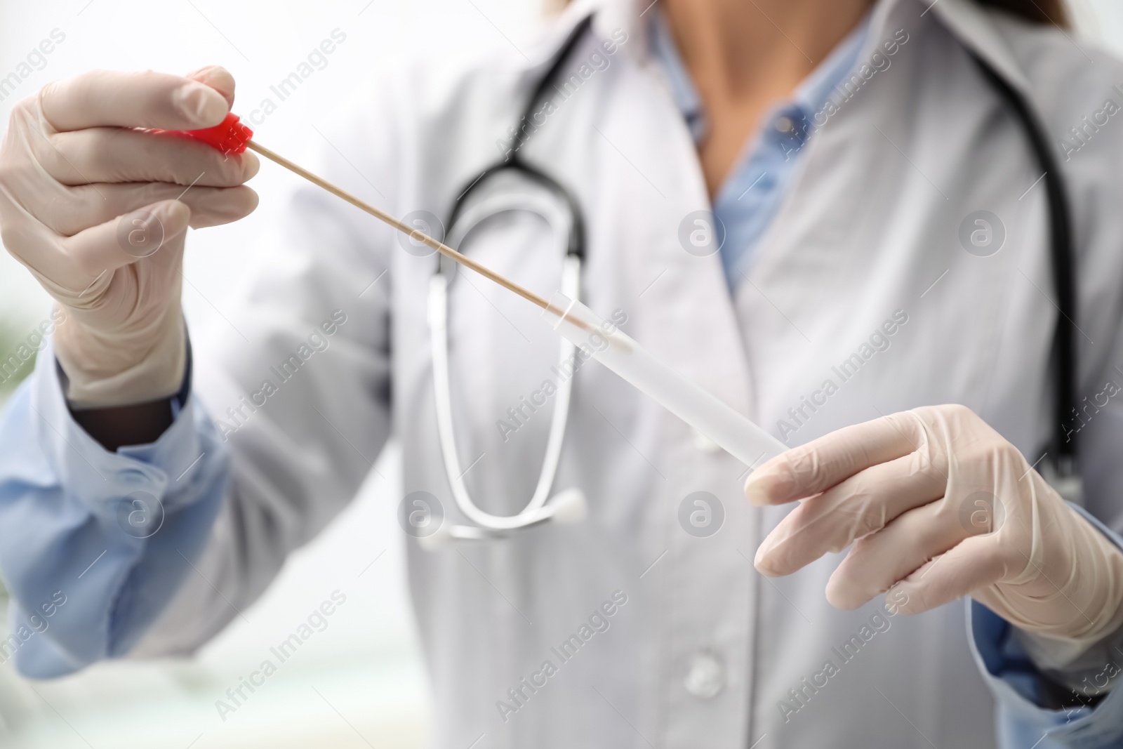 Photo of Doctor holding buccal cotton swab and tube for DNA test in clinic, closeup