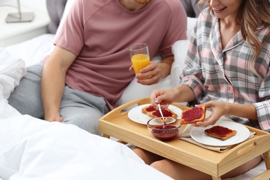 Happy young couple having romantic breakfast in bed at home, closeup