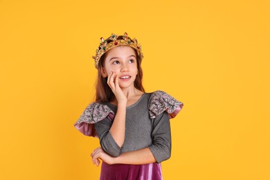 Photo of Cute girl in fairy dress and golden crown with gems on yellow background. Little princess