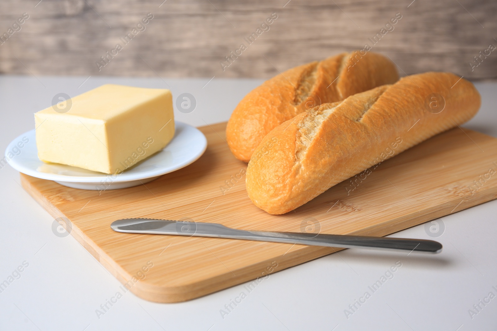 Photo of Tasty baguettes with fresh butter on white table