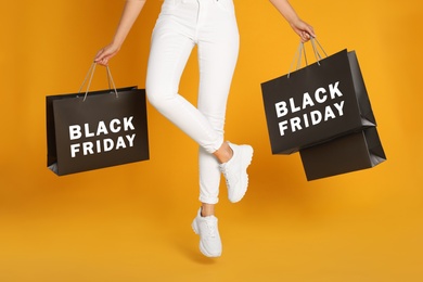 Photo of Woman with shopping bags on yellow background, closeup. Black Friday