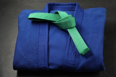 Photo of Green karate belt and blue kimono on gray background, closeup