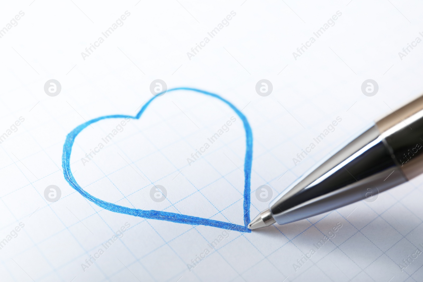 Photo of Drawing heart with pen on sheet of paper, closeup