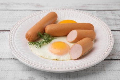 Photo of Delicious boiled sausages, fried eggs and dill on wooden table, closeup