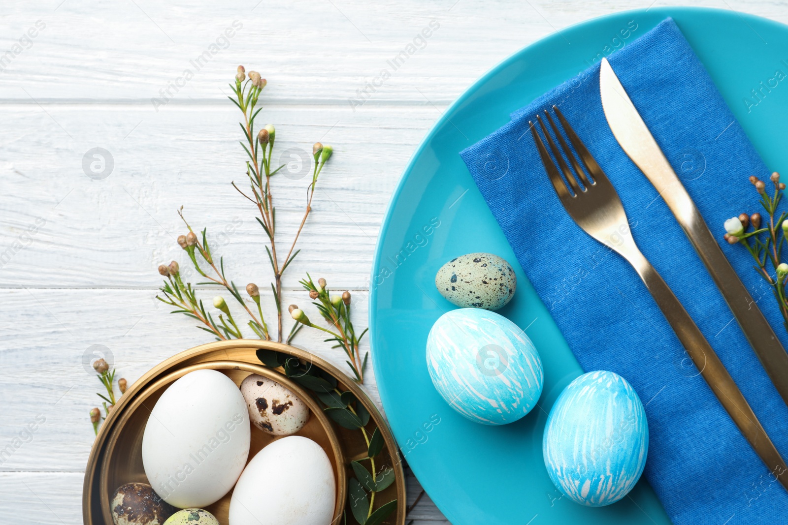 Photo of Festive Easter table setting with eggs and floral decoration on wooden background, flat lay