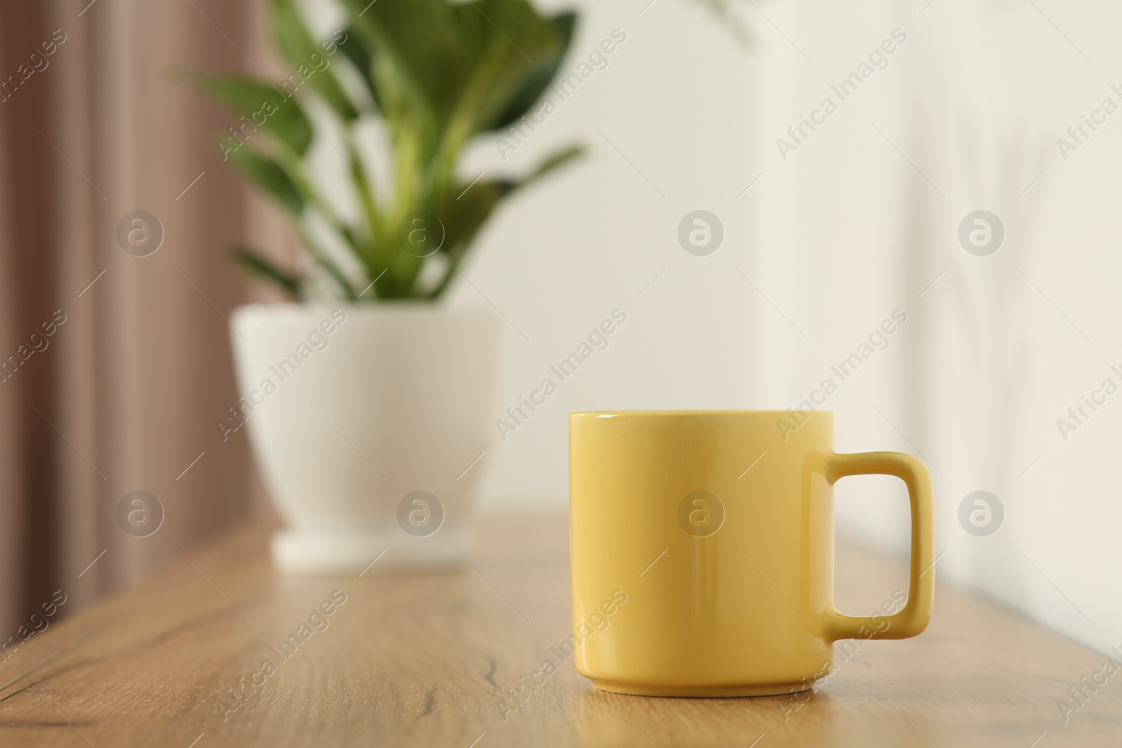 Photo of Yellow mug on wooden table indoors. Mockup for design