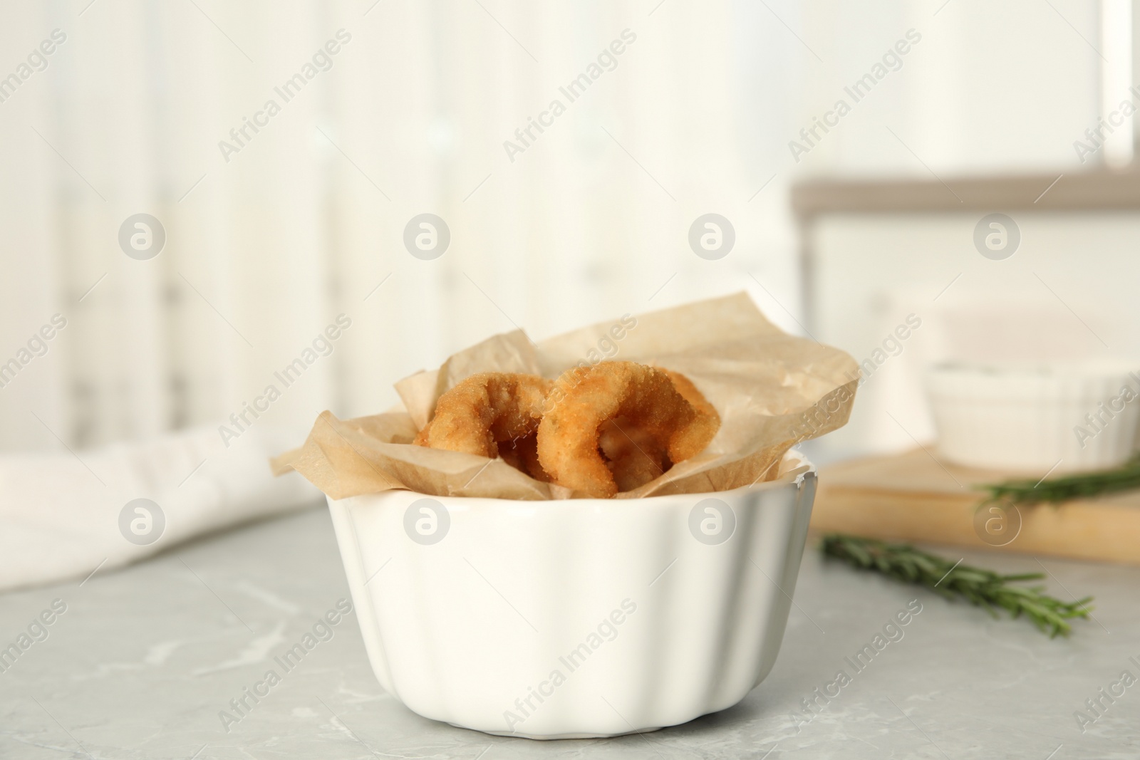 Photo of Delicious crunchy fried onion rings on grey marble table indoors