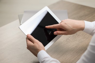 Man using tablet at wooden table, closeup