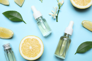 Photo of Flat lay composition with bottles of citrus essential oil on light blue background