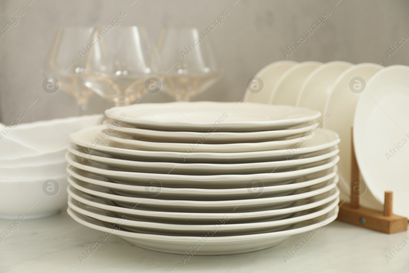 Photo of Clean plates, bowls and glasses on white marble table