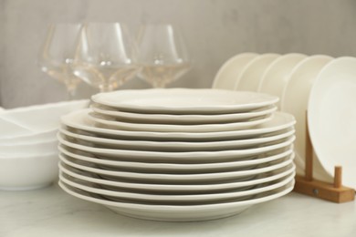 Clean plates, bowls and glasses on white marble table