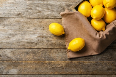 Flat lay composition with crate of lemons and fabric on wooden background