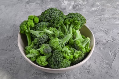 Photo of Bowl of fresh raw broccoli on grey textured table