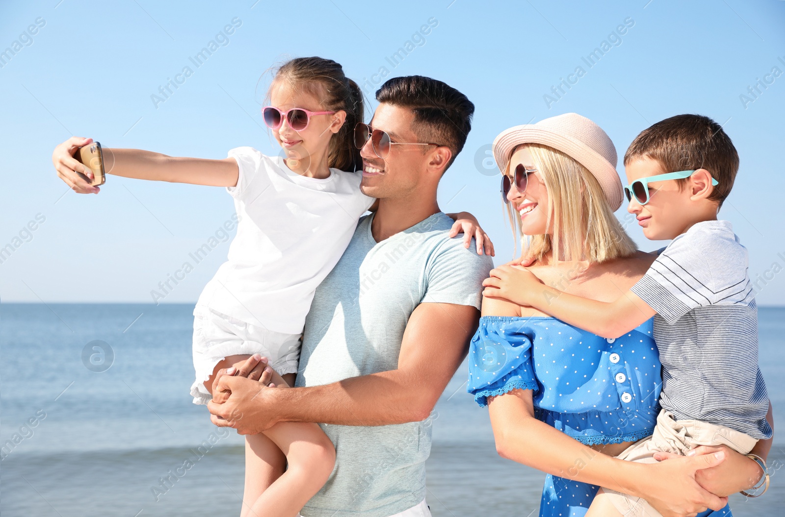 Photo of Happy family taking selfie at beach on sunny day