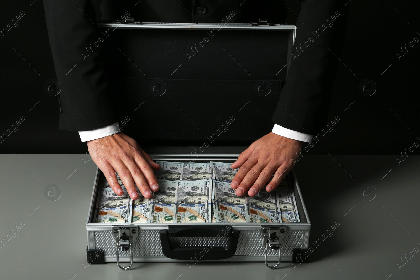 Photo of Businessman with suitcase full of money on dark background