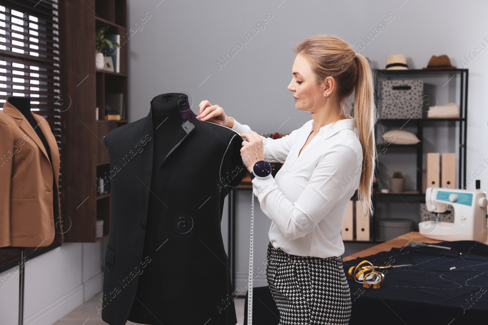 Photo of Dressmaker with measuring tape working in atelier